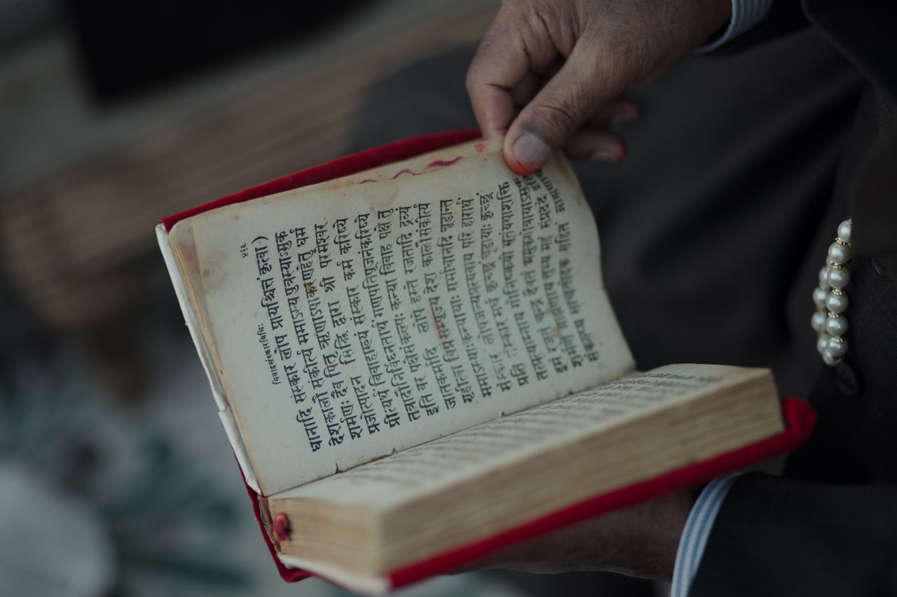 Mastering the First Impression: Your intriguing post title goes here A hand holding an ancient book with Sanskrit text, symbolizing cultural heritage.